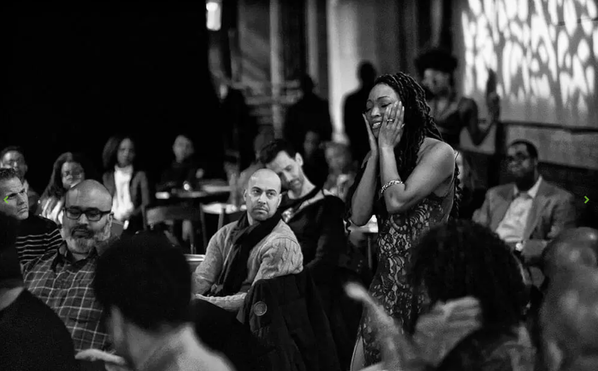 Black and white photo of a performer moving among seated audience members