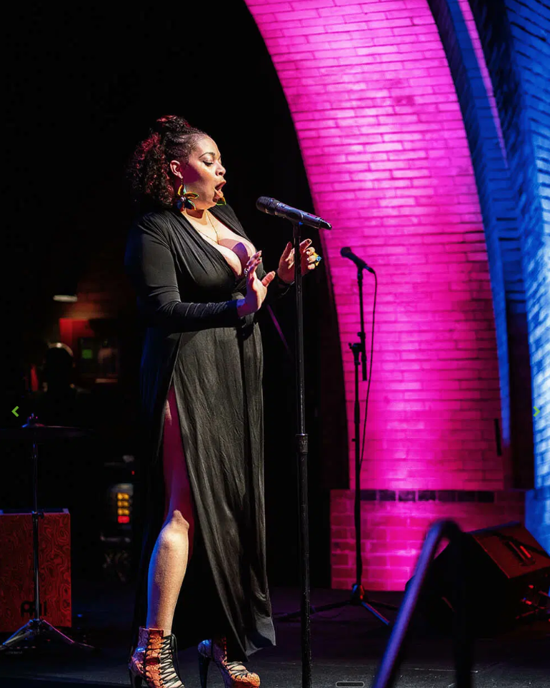 Vocalist singing under a magenta-lit brick arch